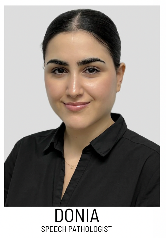 Portrait of Donia, a speech pathologist, smiling in a black shirt against a light gray background.